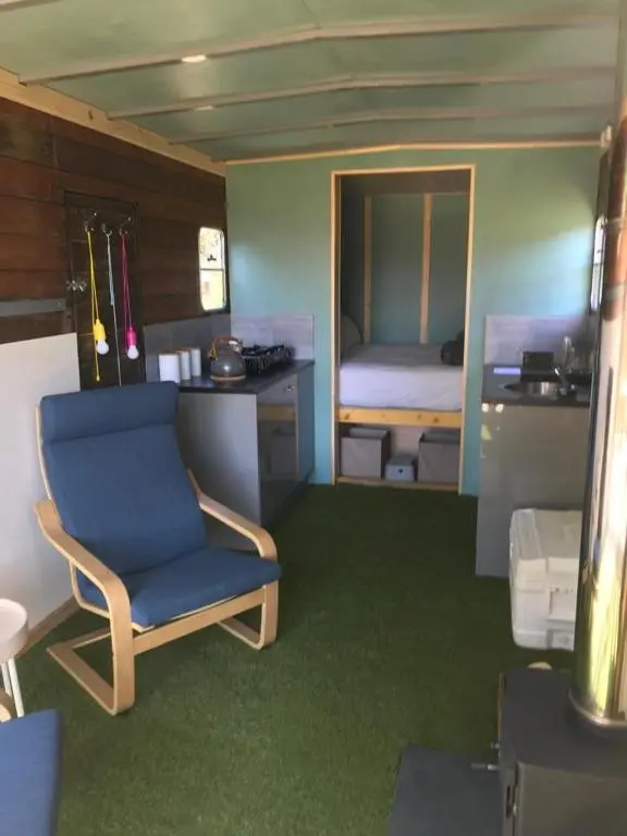 a room with a blue chair and a bedroom at Highland Shepherd Huts in Nethy Bridge