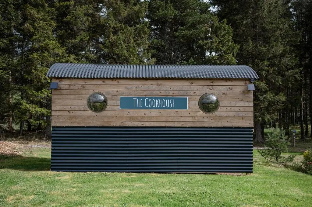 a wooden building with a sign that reads the conjure at Highland Shepherd Huts in Nethy Bridge