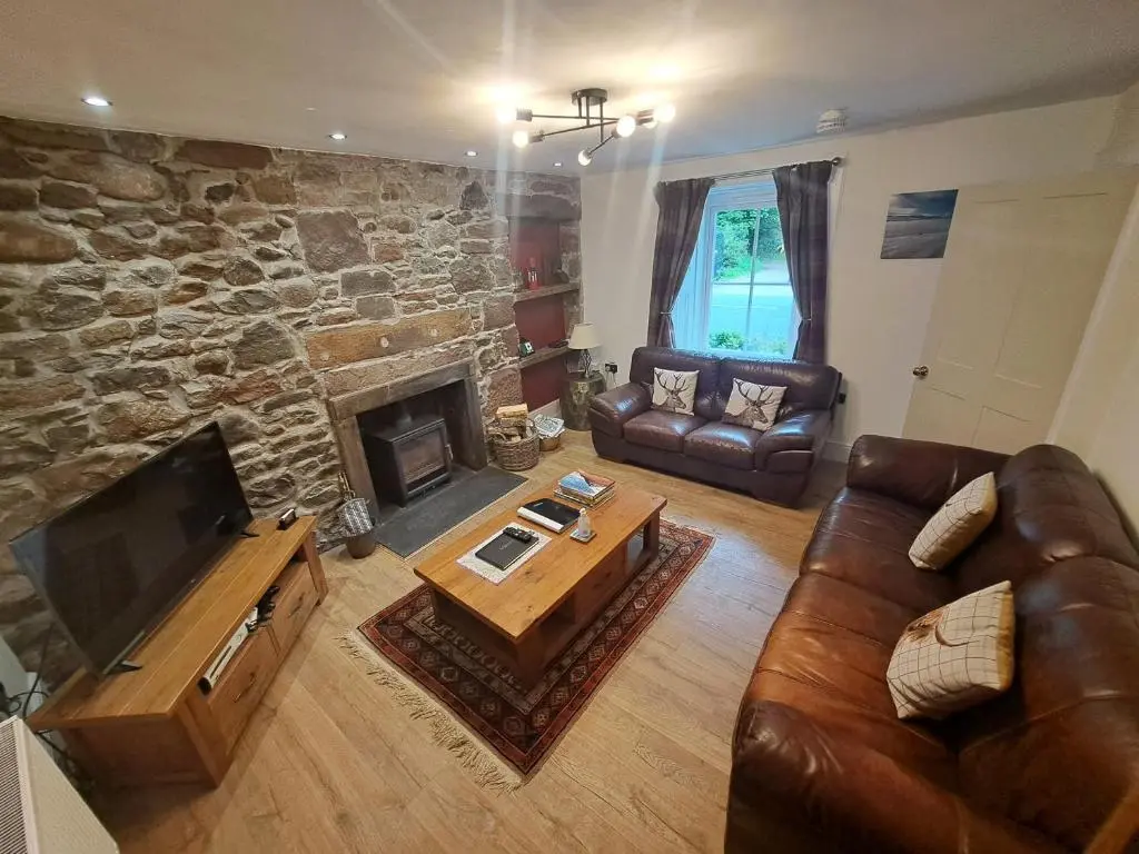 a living room with a couch and a fireplace at Clematis Cottage, Fortrose in Fortrose