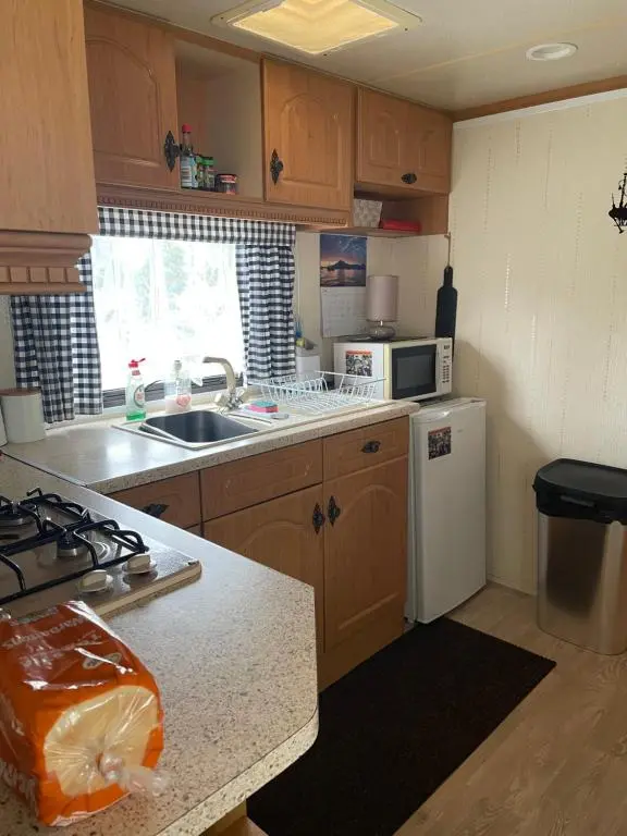 a kitchen with wooden cabinets and a white refrigerator at Caravan at Charleston House in Inverness