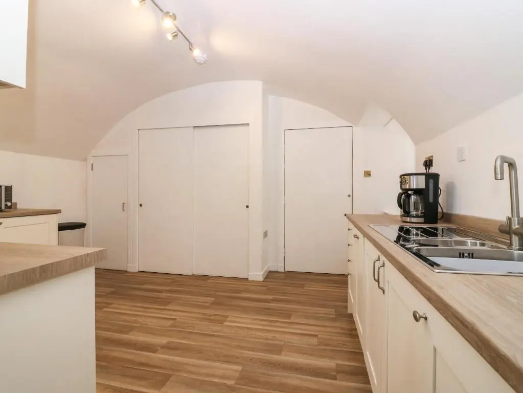 a kitchen with white cabinets and wooden floors at East Wing - Castle Fraser in Inverurie