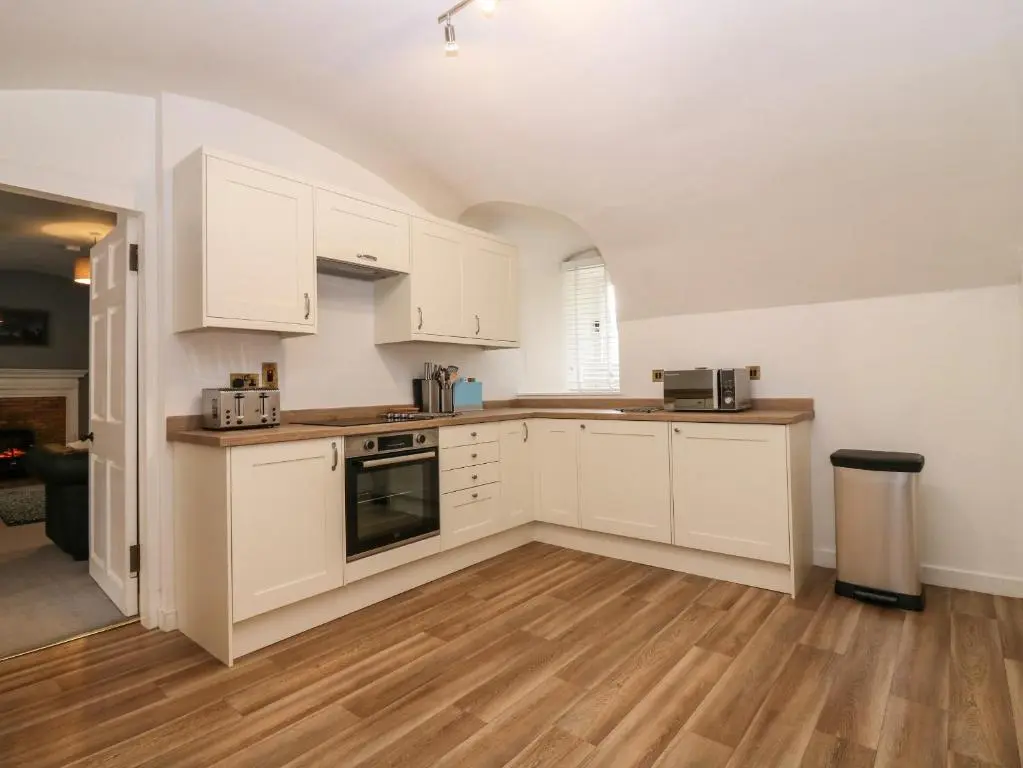 a kitchen with white cabinets and a wooden floor at East Wing - Castle Fraser in Inverurie