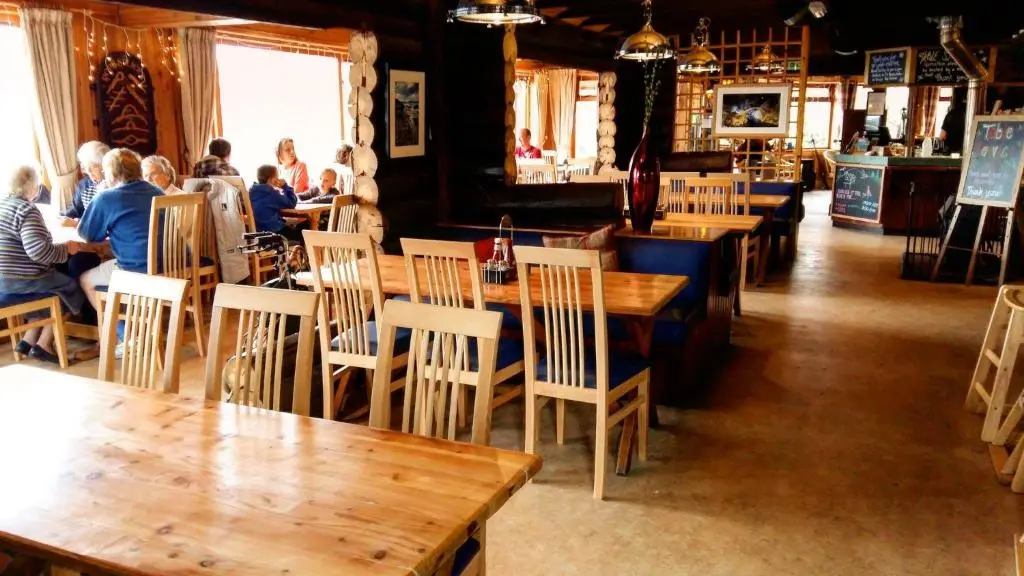 a restaurant with wooden tables and people sitting at tables at Loch Insh Chalets and Apartments in Kincraig