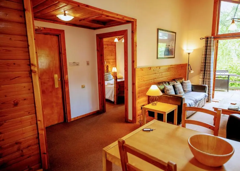 a living room with a couch and a table at Loch Insh Chalets and Apartments in Kincraig