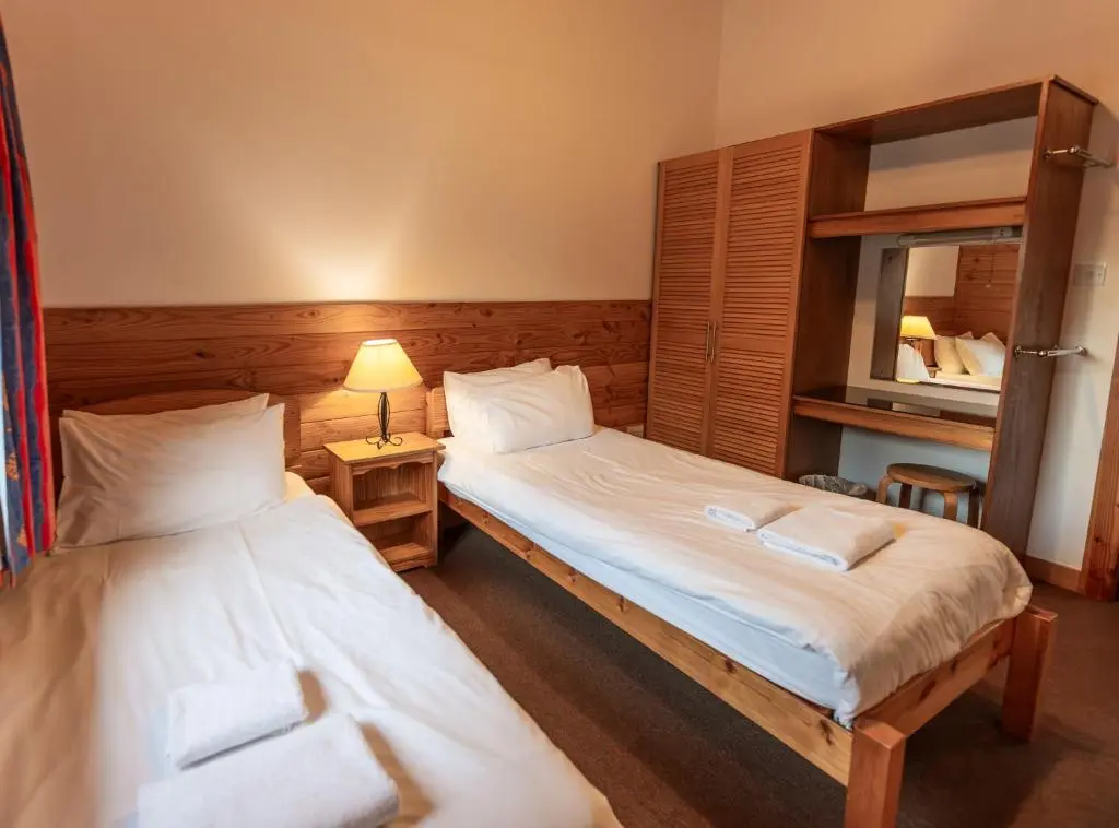 two twin beds in a room with a mirror at Loch Insh Chalets and Apartments in Kincraig