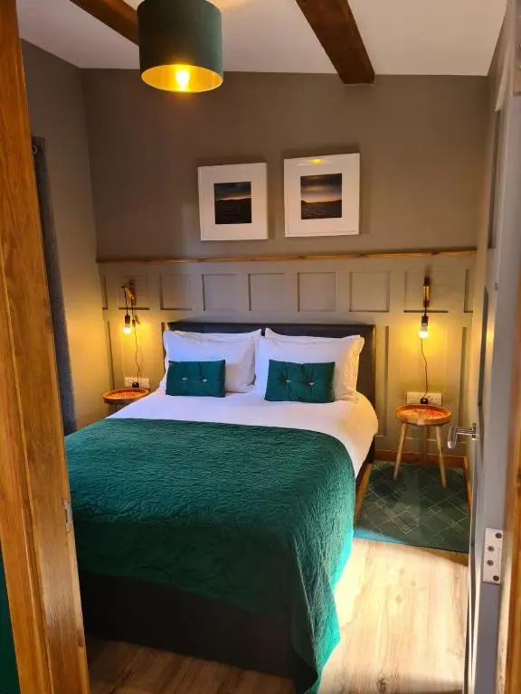 a bedroom with a large bed with a green blanket at The Hide in Ullapool