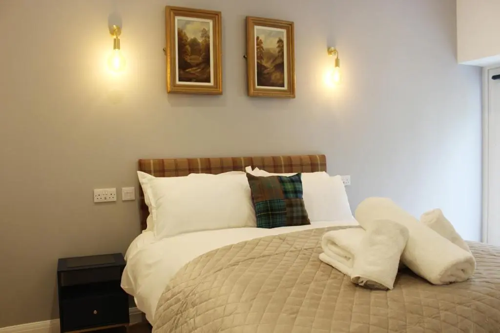a bedroom with a bed with two pictures on the wall at Conon Hotel in Dingwall