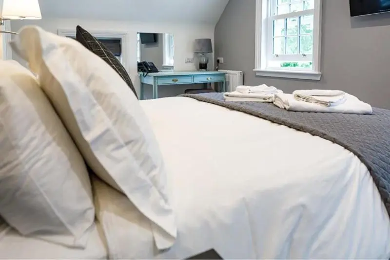 a bed with white sheets and pillows in a bedroom at Conon Hotel in Dingwall