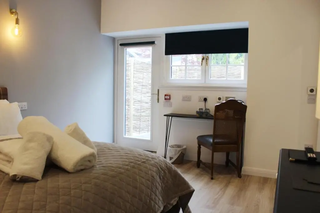 a bedroom with a bed and a desk and a window at Conon Hotel in Dingwall