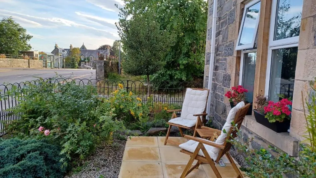 two chairs sitting on a patio next to a building at Gynack Villa in Kingussie