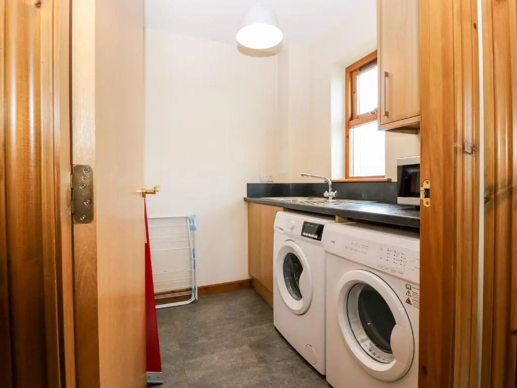 a laundry room with a washing machine and a sink at Kilnary Cottage in Ellon