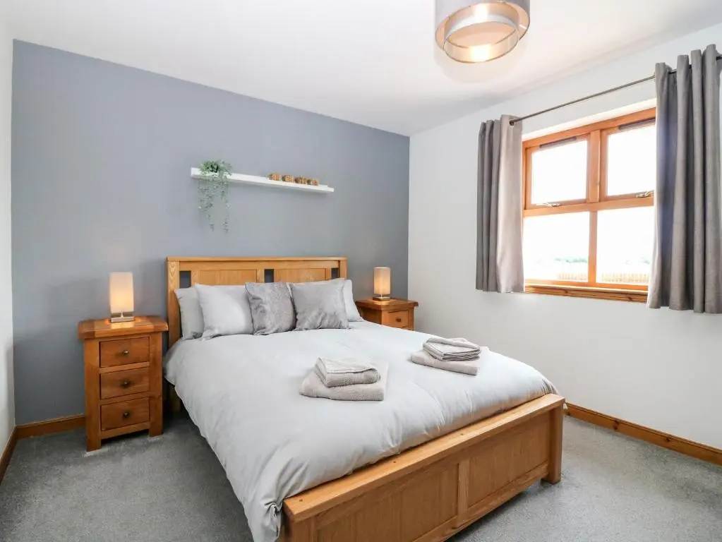 a bedroom with a large bed and a window at Kilnary Cottage in Ellon
