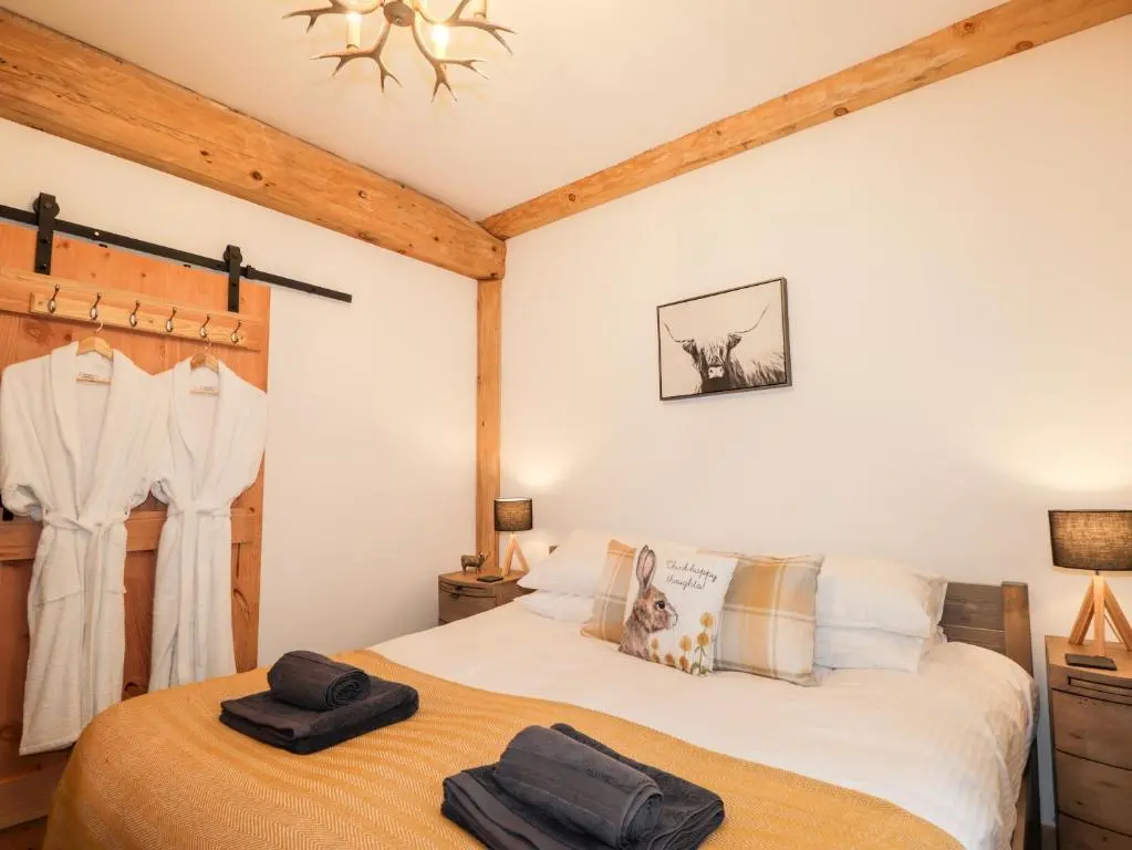 a bedroom with a bed with two towels on it at Pine Marten Lodge in Grantown on Spey