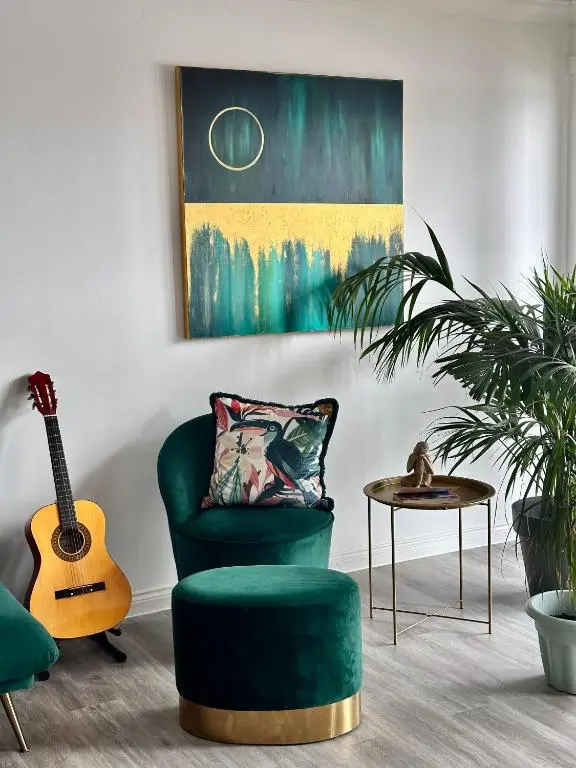 a living room with a green chair and a guitar at The Meadow, River view apartment in South Kessock