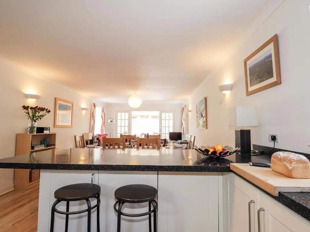 a kitchen and living room with a counter and stools at Redburn Steading in Nairn