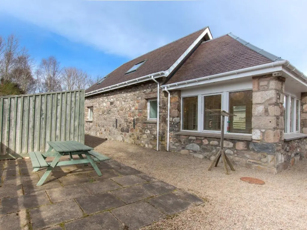 a stone house with a picnic table in front of it at Redburn Steading in Nairn