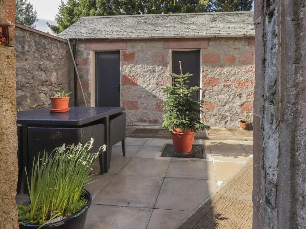 a patio with two plants in pots next to a building at Old Manse in Muir of Ord