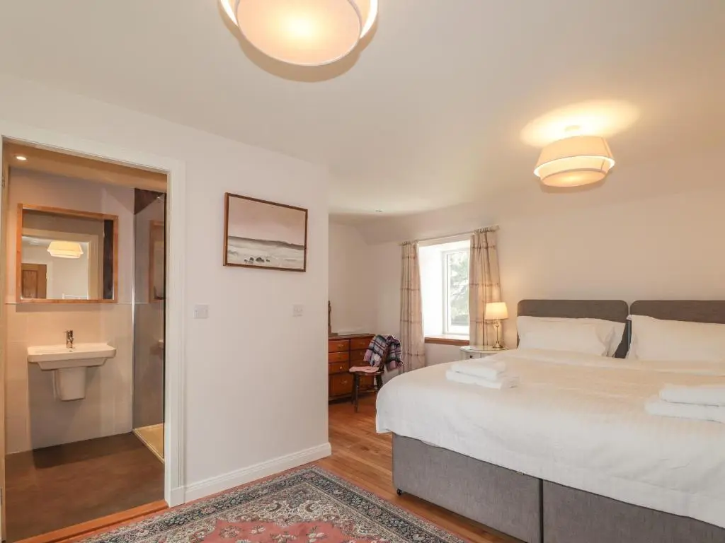 a bedroom with a large bed and a bathroom at Old Manse in Muir of Ord