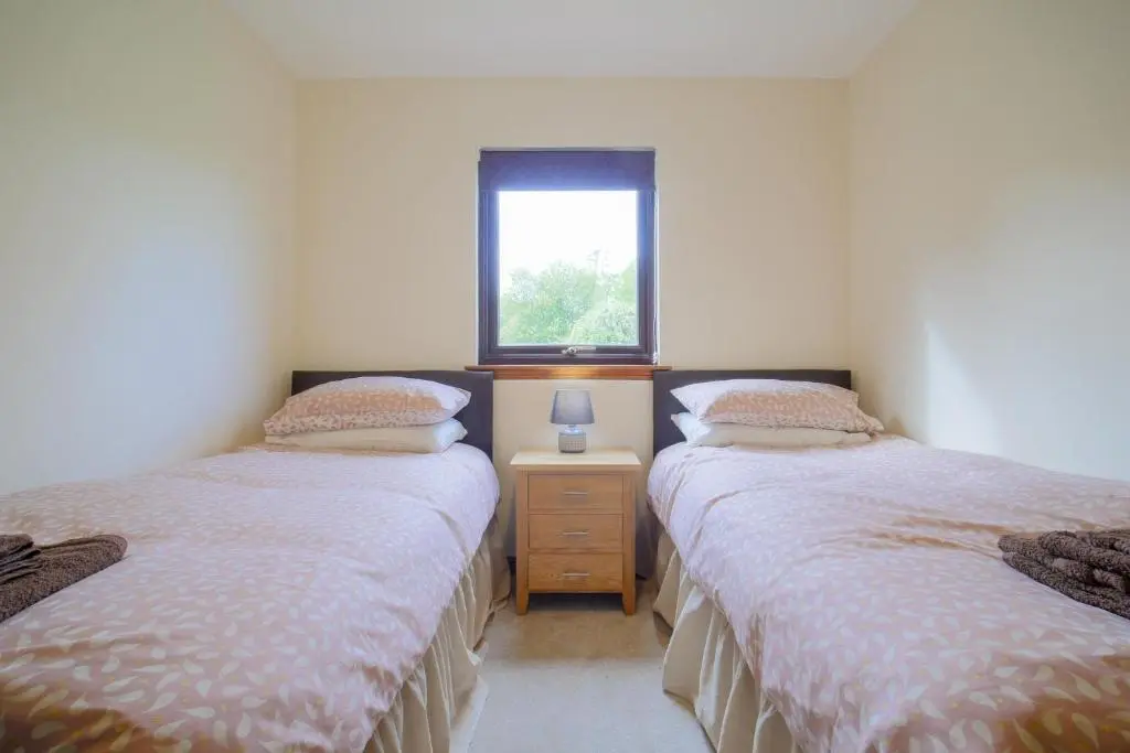 two twin beds in a room with a window at Glenview Chalet Park in Inverness