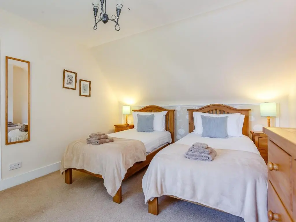 a bedroom with two beds and a mirror at Willow Cottage - Uk39244 in Inverness