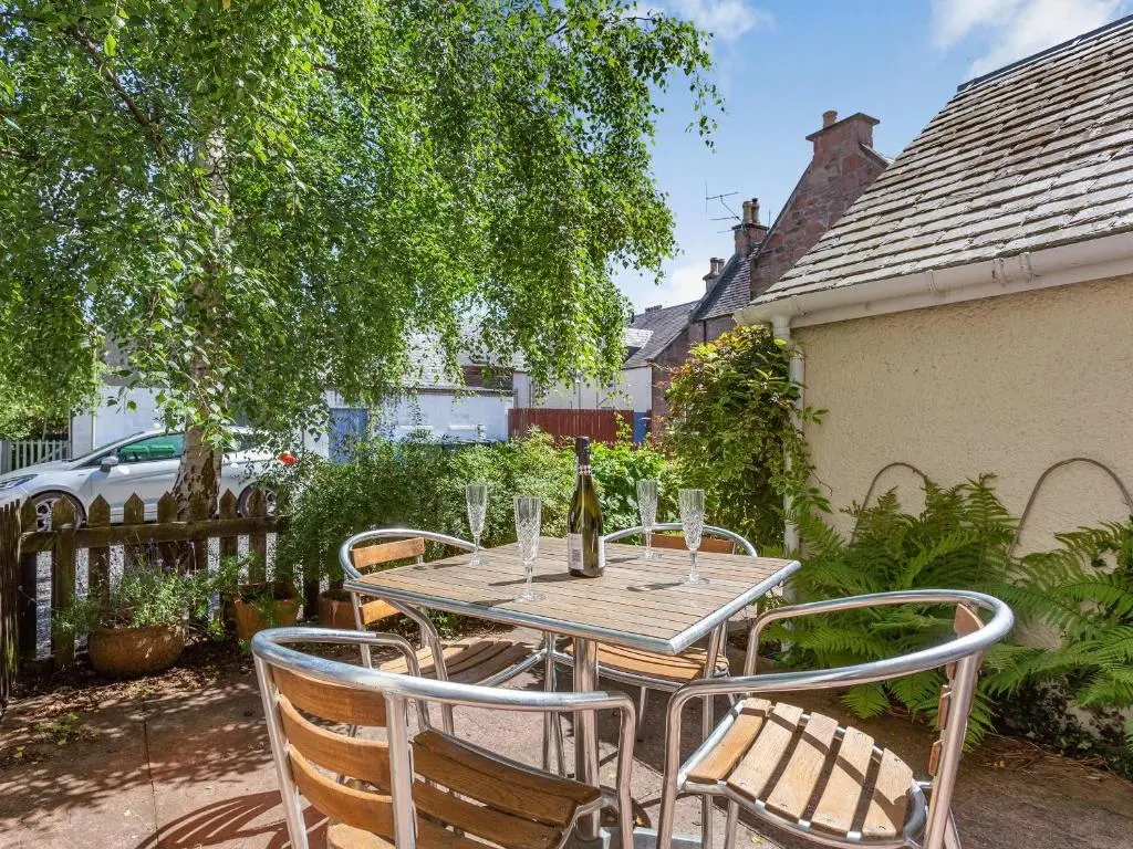 a table with three chairs and a bottle of wine at Willow Cottage - Uk39244 in Inverness