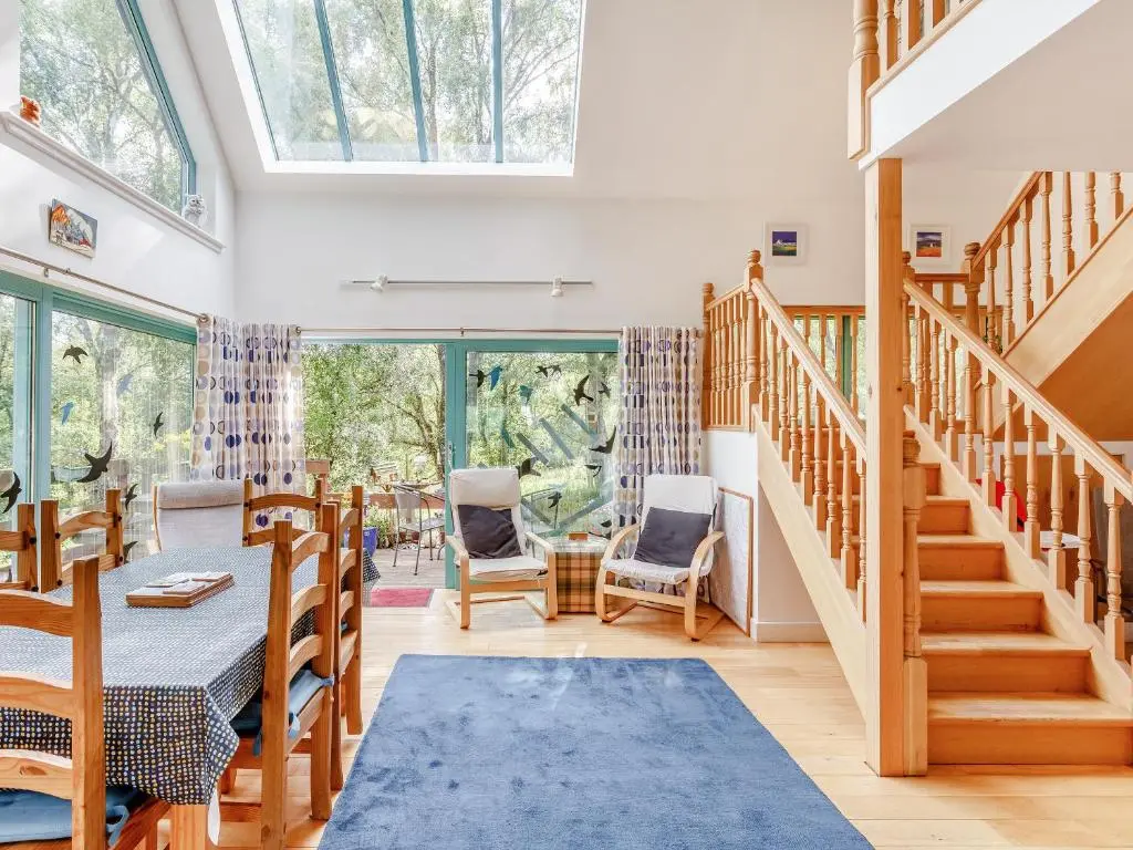 a room with stairs and a table and chairs at Ptarmigan Cottage-Ukc5518 in Boat of Garten