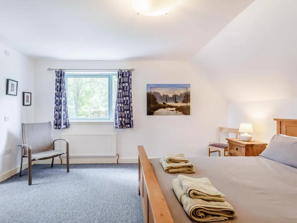 a bedroom with a bed and a chair and a window at Ptarmigan Cottage-Ukc5518 in Boat of Garten
