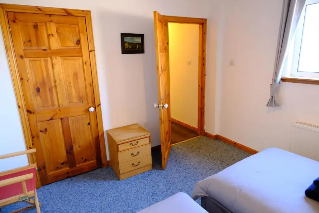 a bedroom with a door and a bed and a table at Lovely 1-bedroom apartment with free parking in Inverness