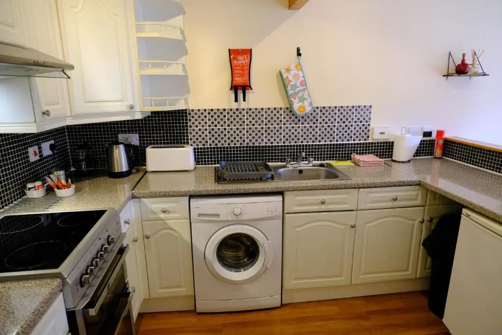 a kitchen with a washing machine and a sink at Lovely 1-bedroom apartment with free parking in Inverness