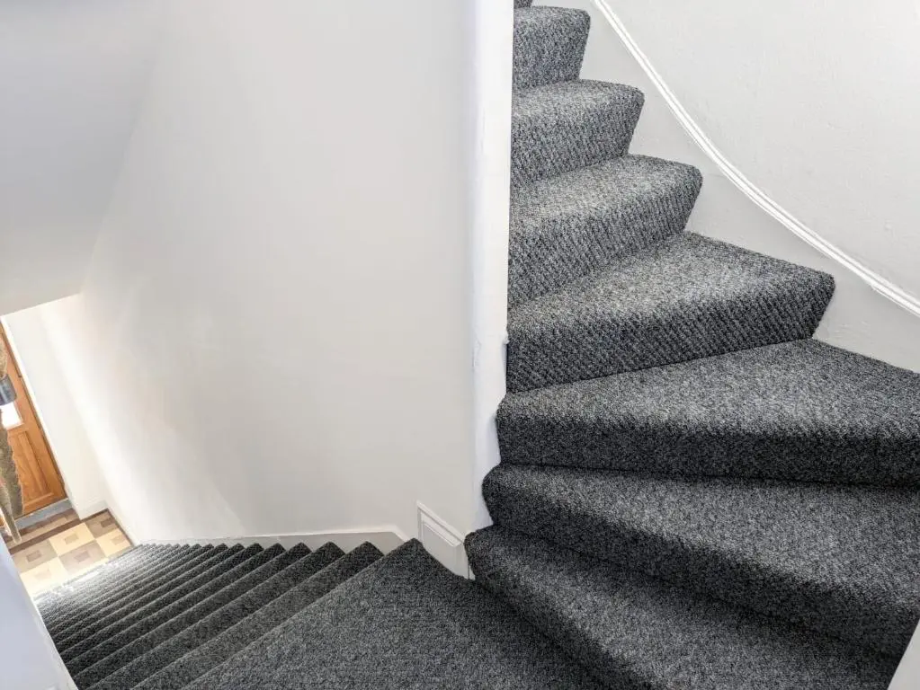 a stairway with grey carpeting and stairs with at 2 Bedroom Townhouse with Seaview on the NC500 Wick in Wick