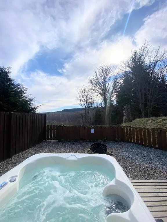 a hot tub in a yard with a fence at Kaoglen-Stags Suite-Hot tub-Cairngorms- Dog Friendly in Balnald