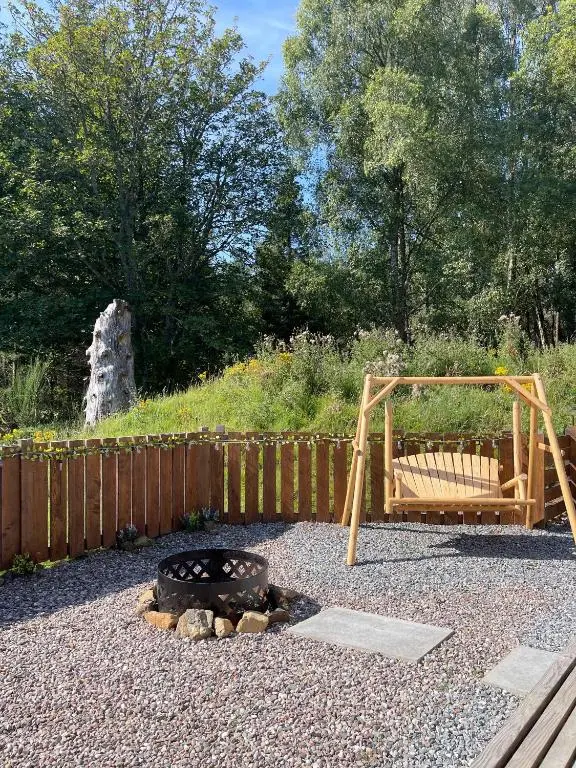 a backyard with a fire pit and a wooden fence at Kaoglen-Stags Suite-Hot tub-Cairngorms- Dog Friendly in Balnald