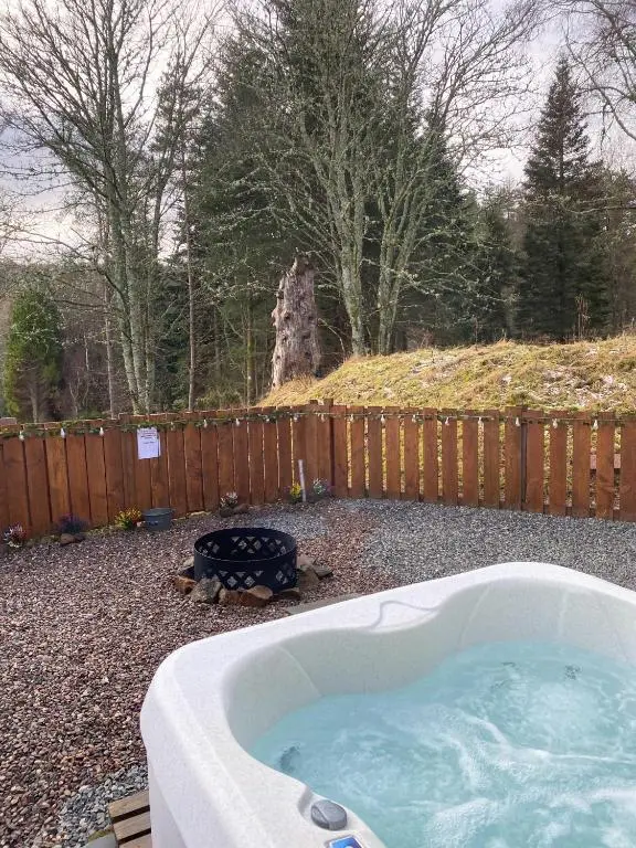 a hot tub in a yard next to a fence at Kaoglen-Stags Suite-Hot tub-Cairngorms- Dog Friendly in Balnald