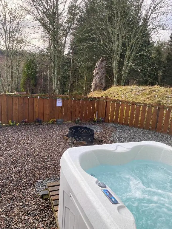 a hot tub in a yard next to a fence at Kaoglen-Stags Suite-Hot tub-Cairngorms- Dog Friendly in Balnald
