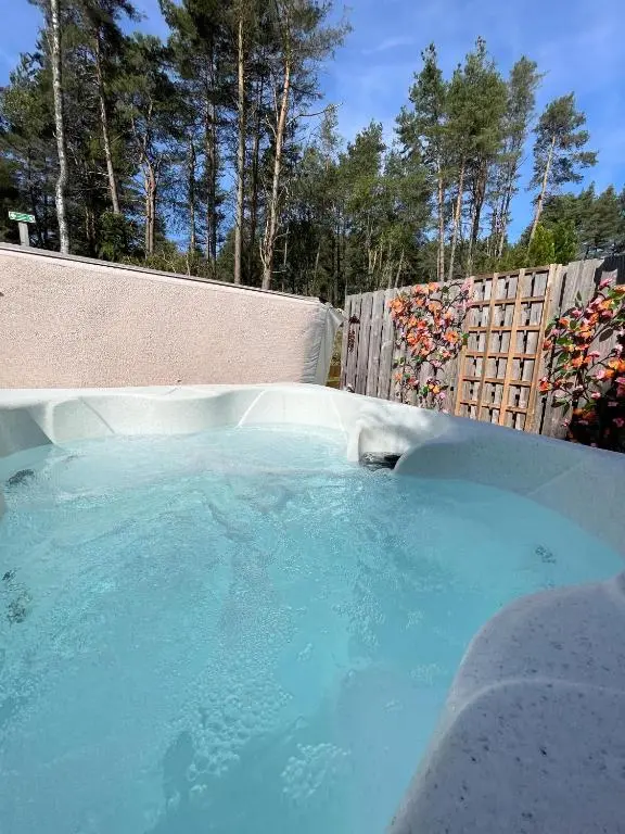 a large pool of blue water next to a fence at Kaoglen-Blossom-Hot tub-Cairngorms-Pet Friendly in Balnald
