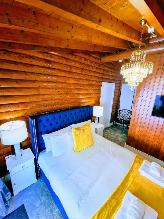 a bed in a room with a wooden wall at Kaoglen Apollo-Hot tub-Cairngorms-Pet friendly in Balnald