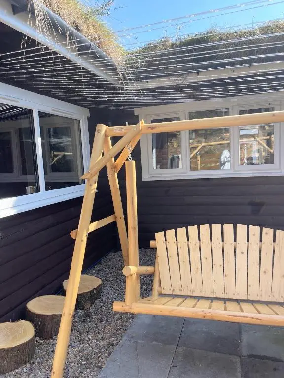 a wooden bench sitting in front of a house at kaoglen Wild-Hot tub-Cairngorms-Pet Friendly in Balnald