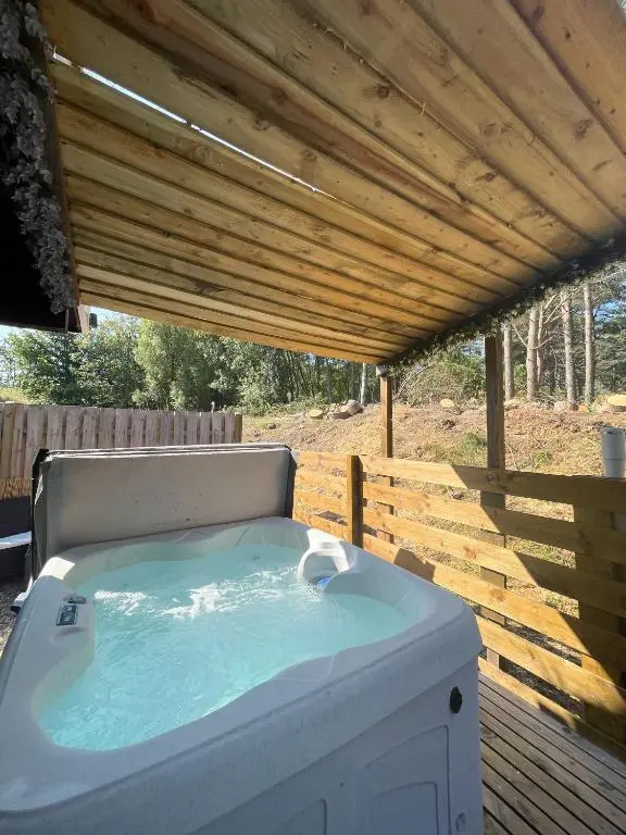a hot tub on a deck with a wooden roof at kaoglen Wild-Hot tub-Cairngorms-Pet Friendly in Balnald