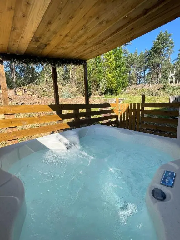 a hot tub in a backyard with a wooden roof at kaoglen Wild-Hot tub-Cairngorms-Pet Friendly in Balnald