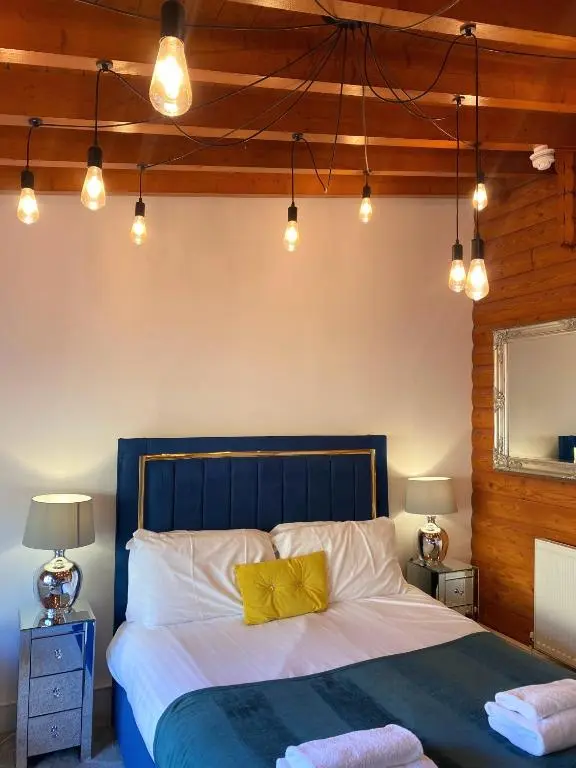 a bedroom with a bed with a blue headboard and lights at Kaoglen Squirrel Drey-Hot Tub-Pet Friendly-Perth in Balnald