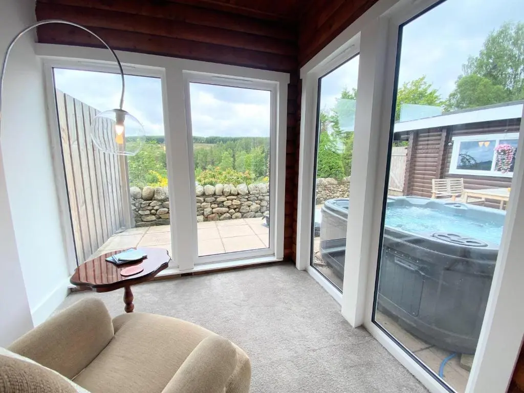 a screened in porch with a view of a hot tub at Kaoglen-GrandSuite-Hot Tub-Pitlochry-Dunkeld-Pet Friendly in Balnald