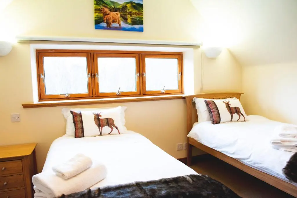 two beds in a room with two windows at Clovenstone Lodges in Inverurie