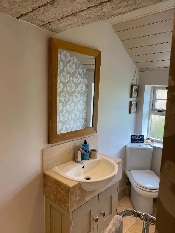 a bathroom with a sink and a toilet and a mirror at Quirky Highland Cottage with Stunning Views in Wester Fearn