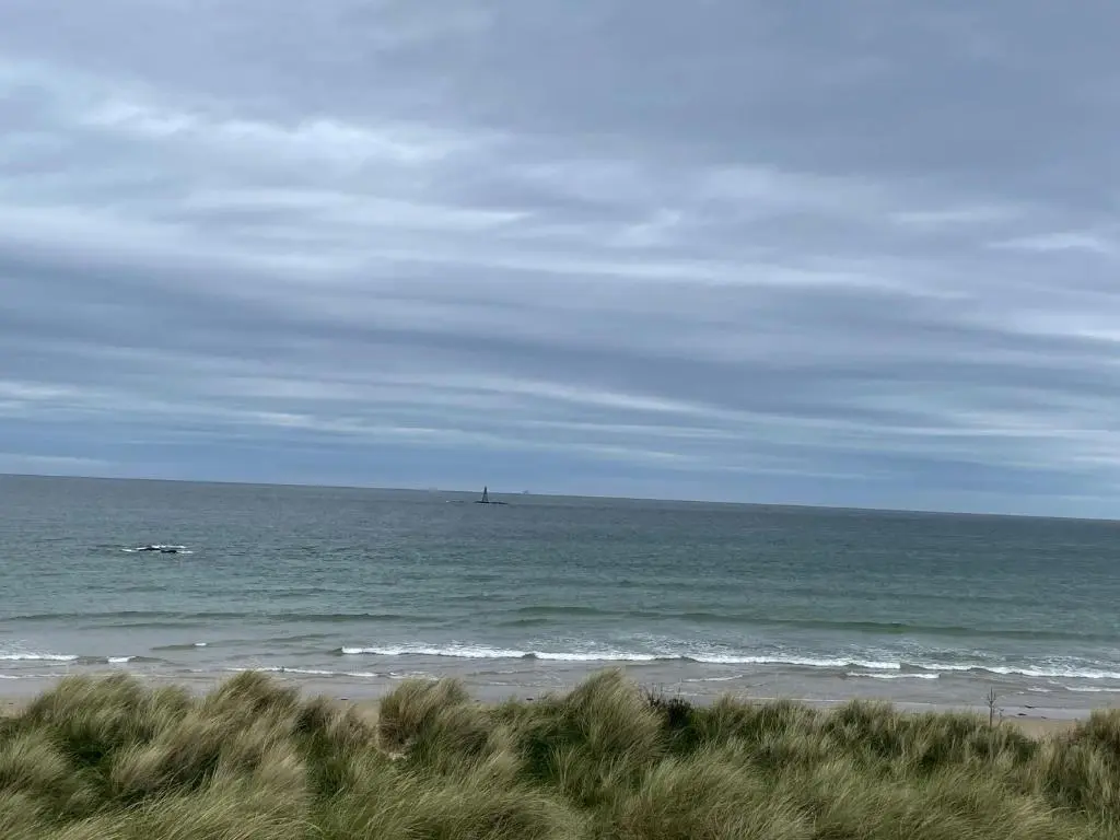 a view of the ocean with a boat in the water at Dune View Caravan in Lossiemouth
