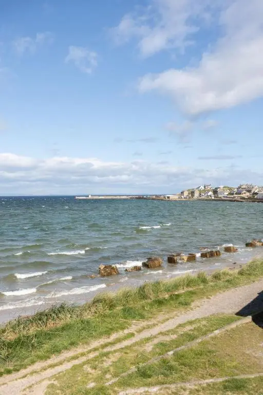 a group of rocks in the water on a beach at The Beach Hut, Burghead in Burghead