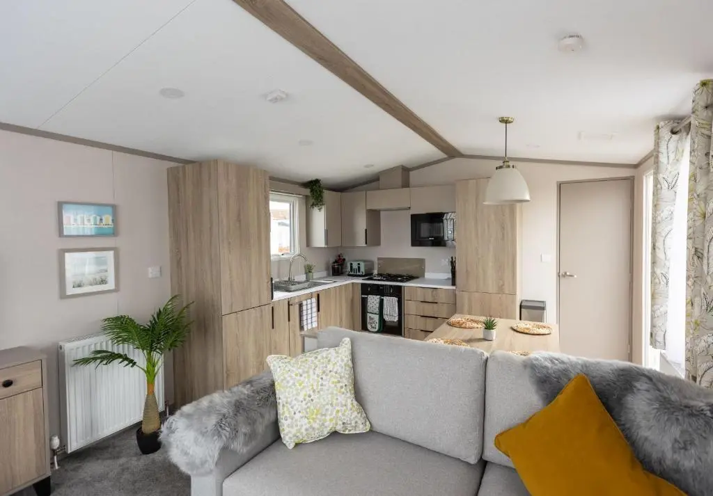 a living room with a couch and a kitchen at The Beach Hut, Burghead in Burghead