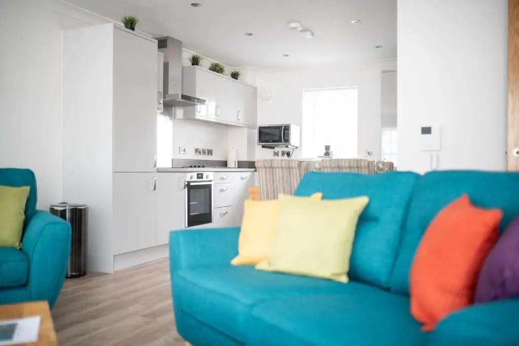 a blue couch with colorful pillows in a living room at Modern Ground Floor Apartment in Tornagrain in Inverness