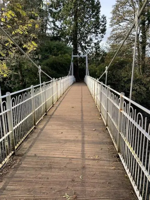 a bridge with a wooden walkway with trees on it at Stylish apartment in the heart of Inverness in Inverness