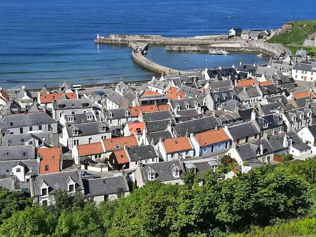 a group of houses on a hill next to the ocean at Creel Cottage Seatown Cullen with Garden in Cullen