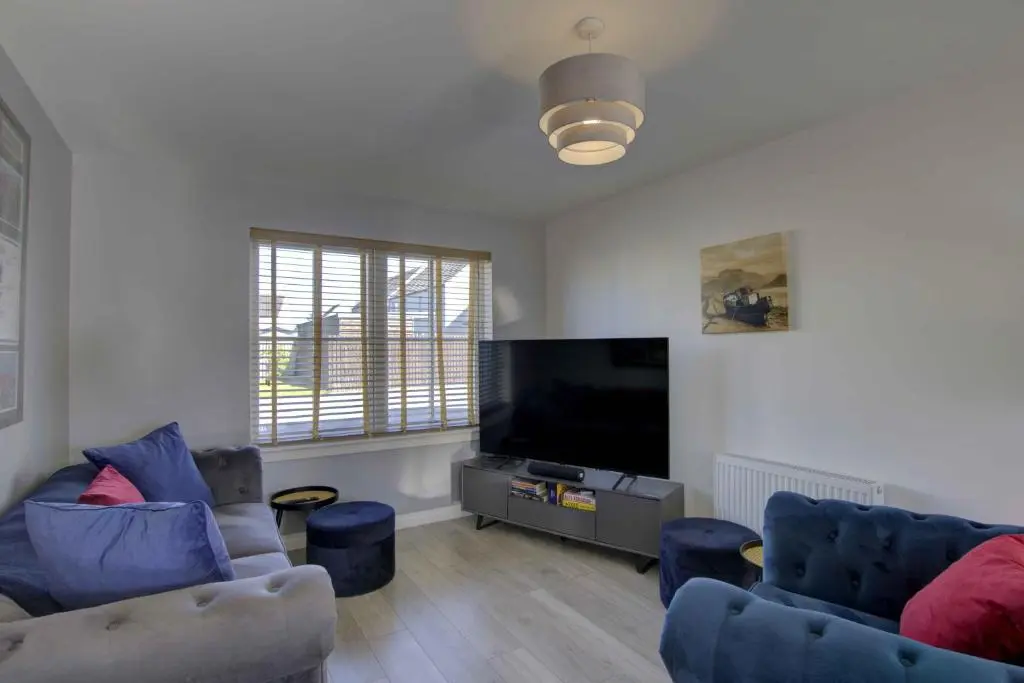 a living room with two couches and a flat screen tv at 3 Mackay Road, Dornoch in Dornoch